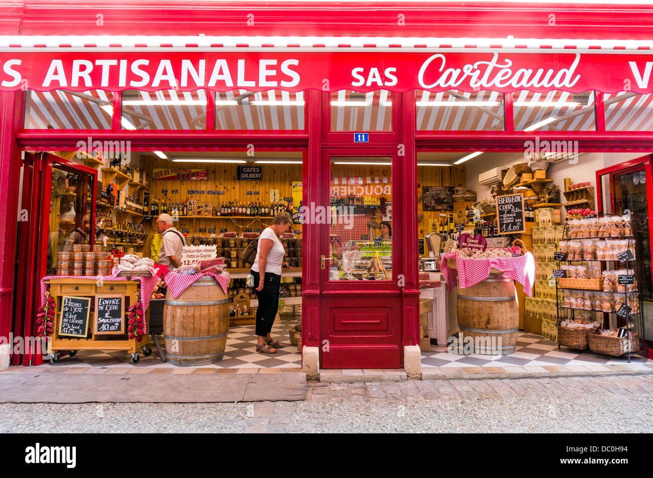 Customers browsing a colourful, specialist food and drink shop in the commune of Brantôme, in the Dordogne in south west France, Europe. Stock Photo