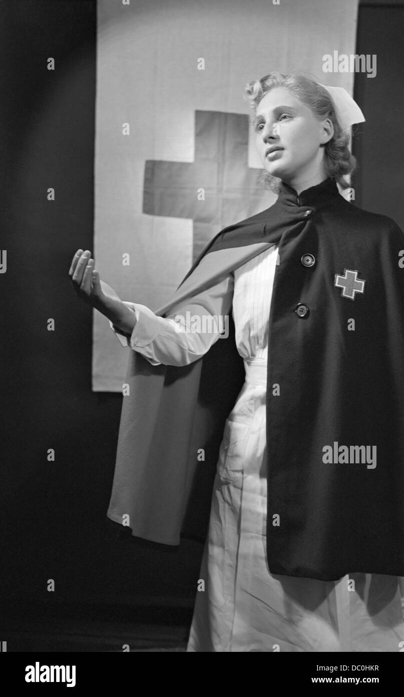 1940s BLOND NURSE WEARING CAPE WITH RED CROSS EXTENDING A HELPING HAND Stock Photo