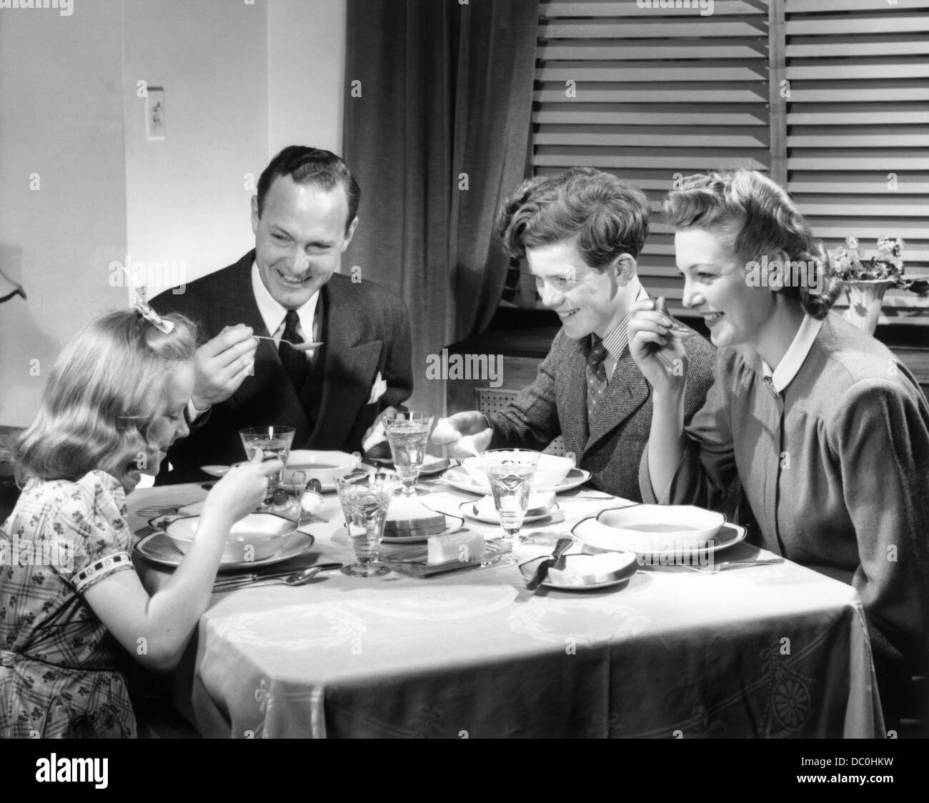 1930s 1940s HAPPY FAMILY EATING DINNER AT HOME Stock Photo