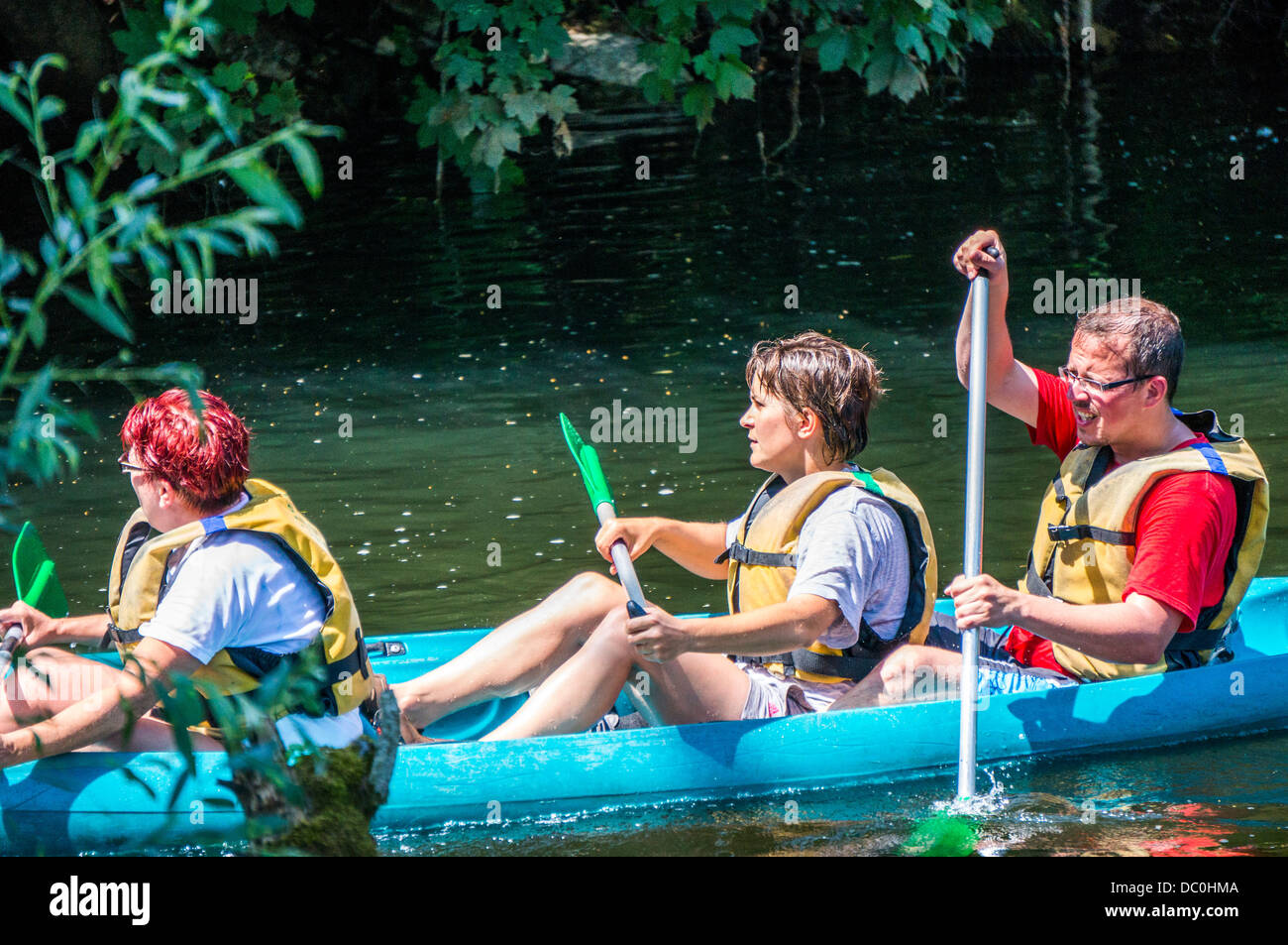 Family of three people in a hire canoe on the river Dronne in the commune of Brantôme, in the Dordogne department in south west France, Europe. Stock Photo