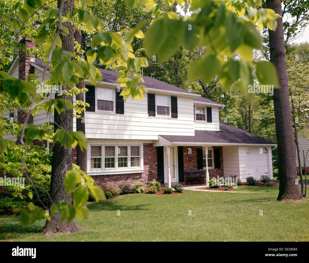 1970s SUBURBAN SPLIT LEVEL HOUSE WITH BLACK SHUTTERS BRICK SIDING AND