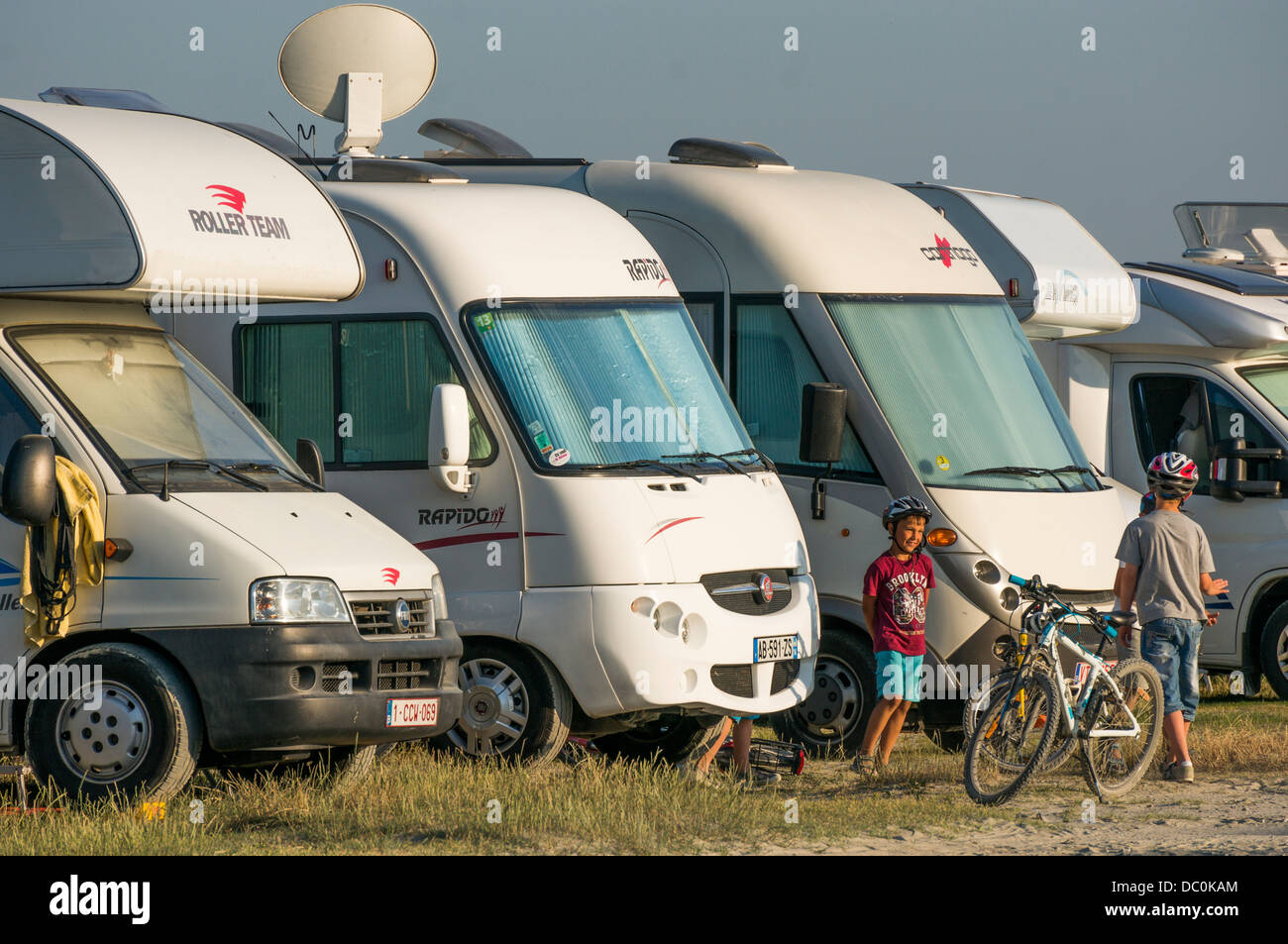 A row of motorhomes and two young boys with bicycles, playing on the aire de camping, Le Crotoy, Somme department, Picardie, northern France, Europe. Stock Photo
