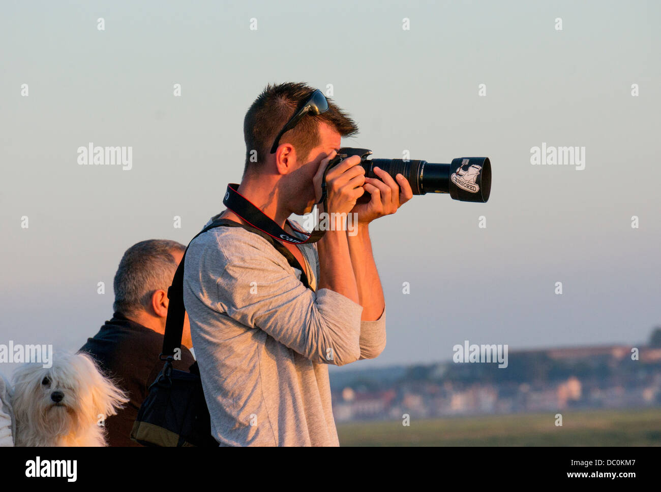 A French photographer taking a picture with a DSLR and extended zoom lens. France, Europe. Stock Photo