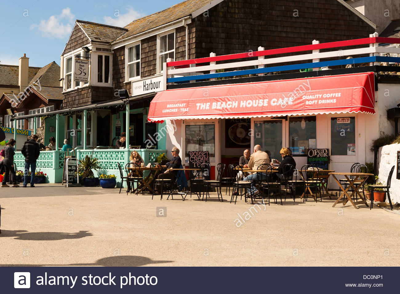 Holiday Makers Enjoy The Sun Outside The Beach House Cafe On The Seafront