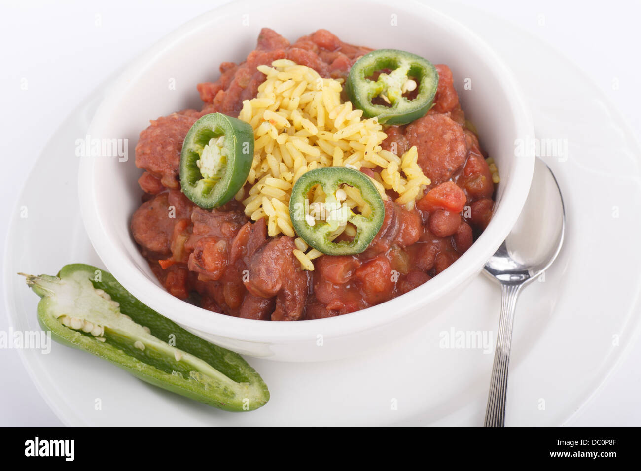 A bowl of red beans and yellow rice with cut jalapeno peppers Stock