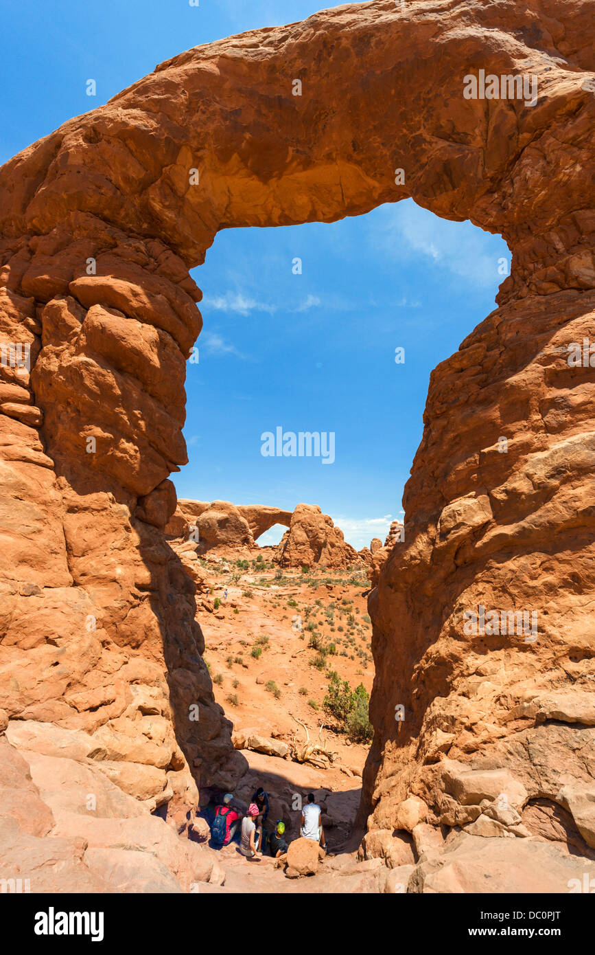 Walkers resting under Turret Arch with South Window arch in the distance, The Windows Section, Arches National Park, Utah, USA Stock Photo
