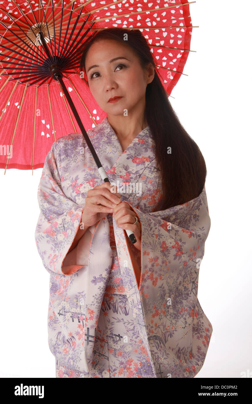 Japanese Lady Wearing a Pink and Lilac Patterned Kimono and Holding a Red Sun Shade. Stock Photo