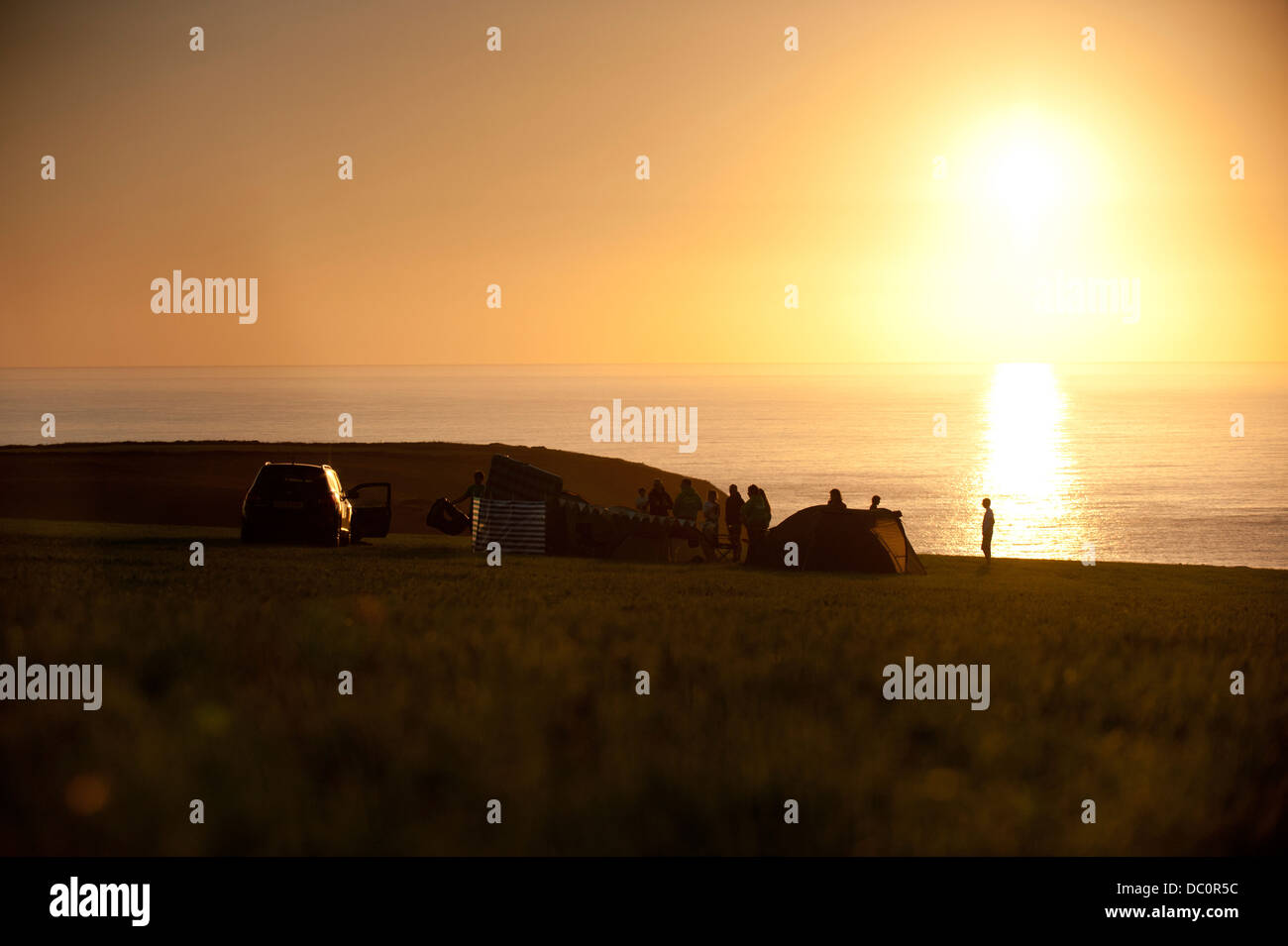 Family camping and enjoying a setting sun near St Davids, Pembrokeshire, Stock Photo