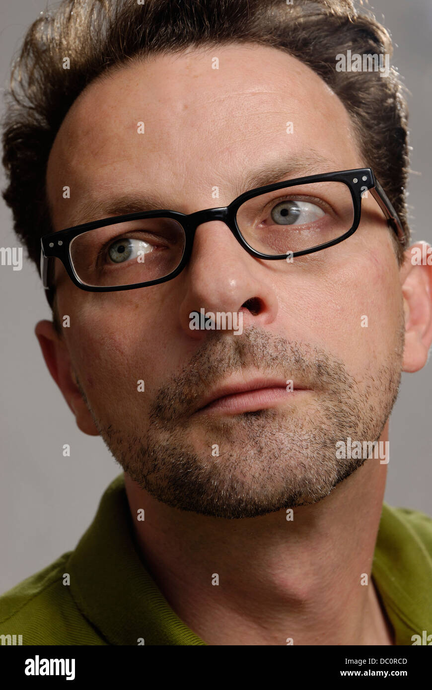 A man with glasses, a green polo shirt and unshaven Stock Photo