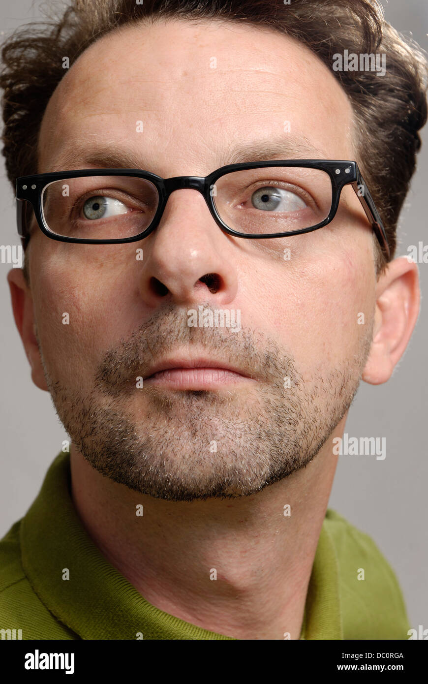 A man with glasses, a green polo shirt and unshaven Stock Photo