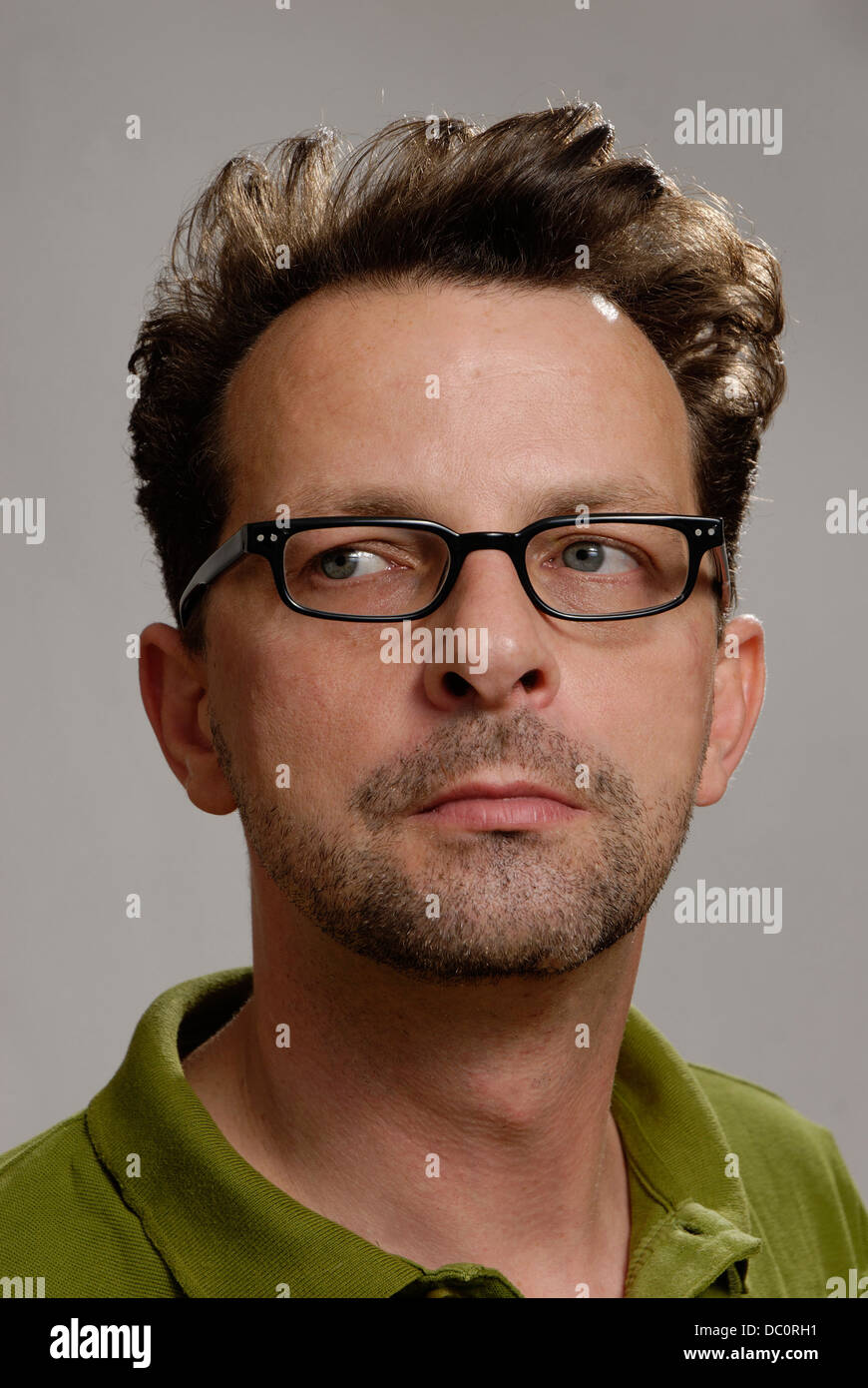 A man with glasses, a green polo shirt and unshaven Stock Photo
