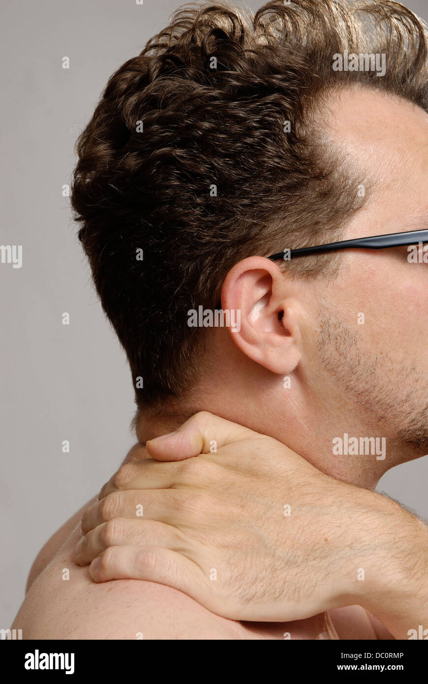 A man with glasses, no shirt and unshaven Stock Photo