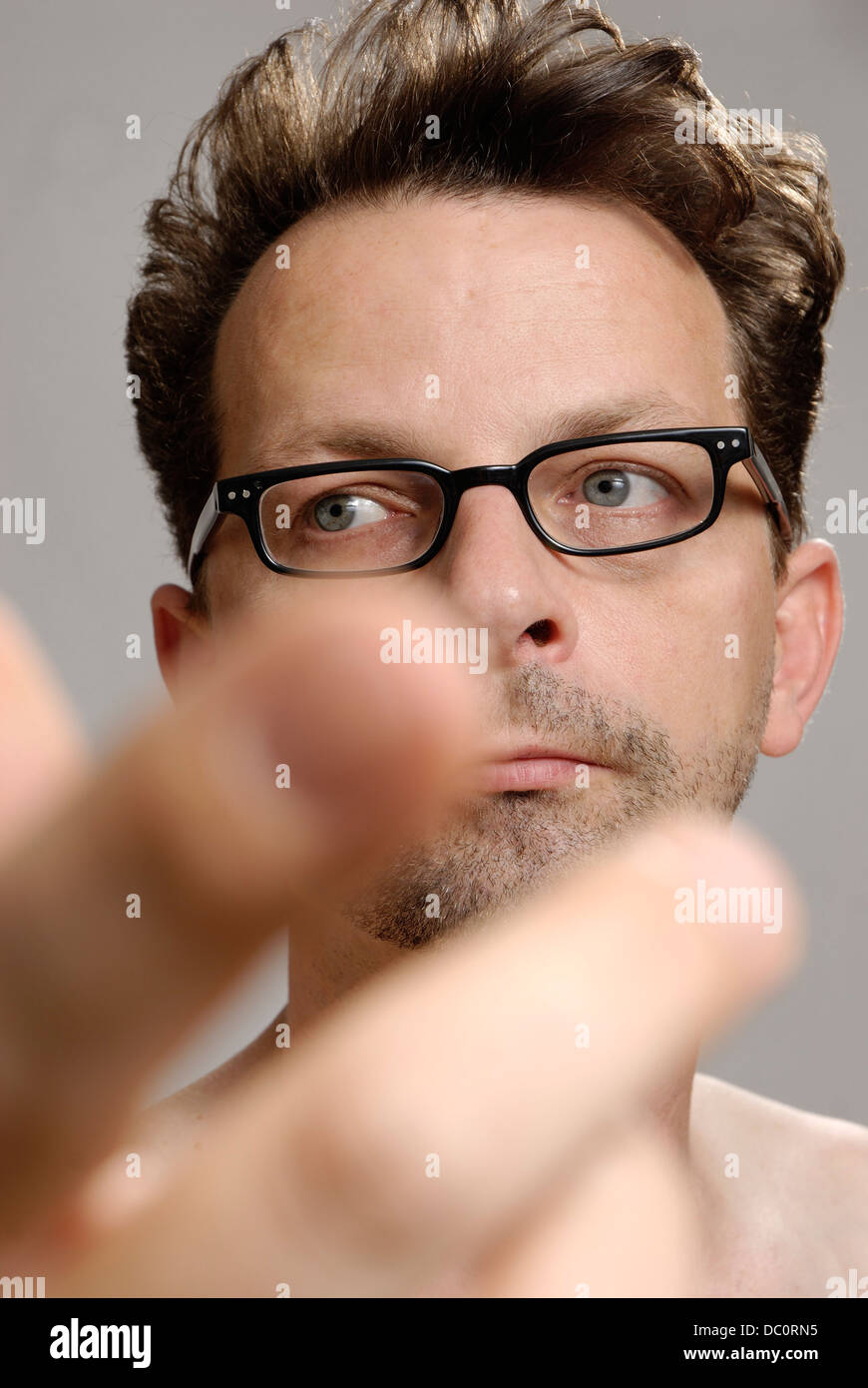 A man with glasses, no shirt and unshaven Stock Photo