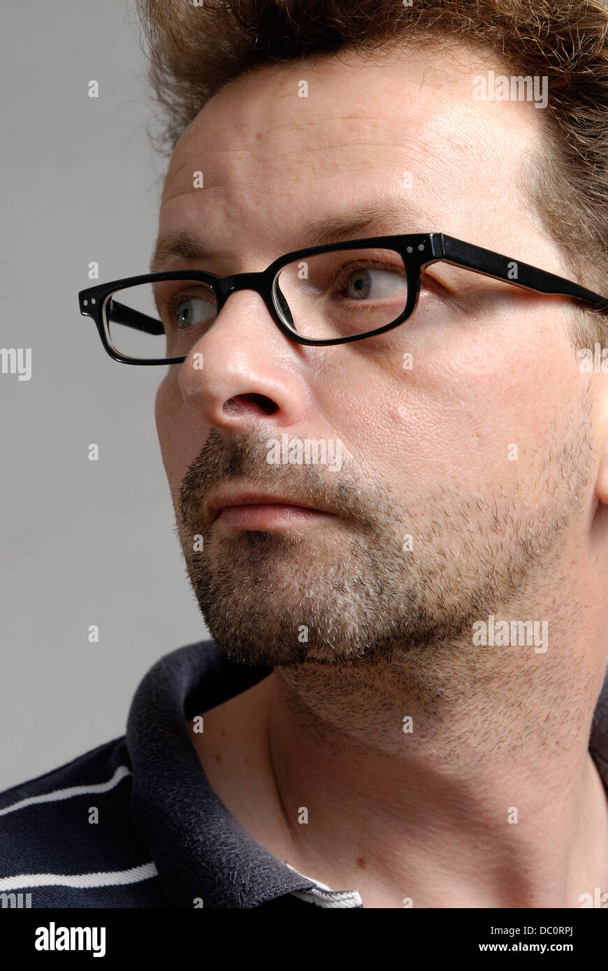 A man with glasses, a blue-white polo shirt and unshaven Stock Photo