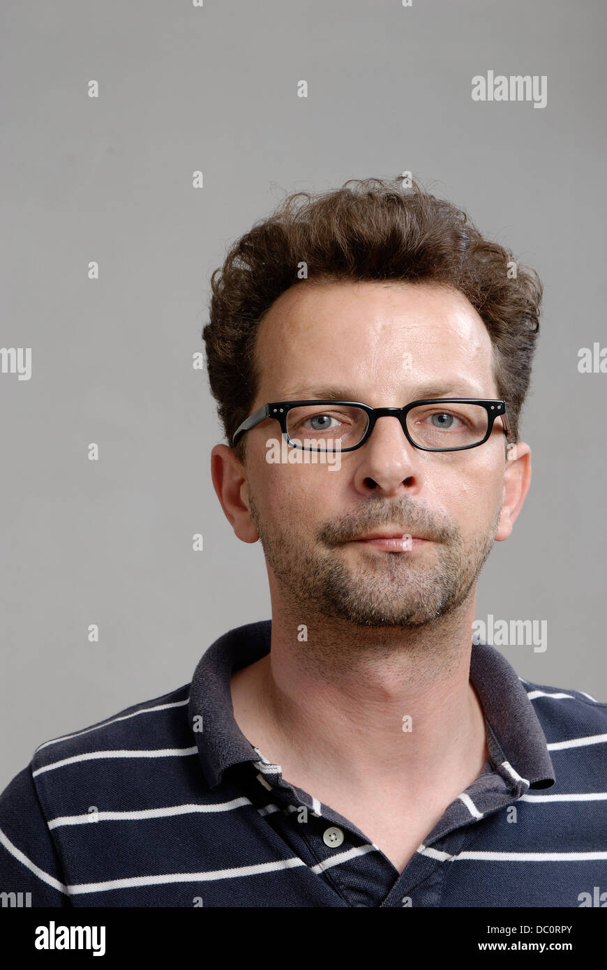 A man with glasses, a blue-white polo shirt and unshaven Stock Photo