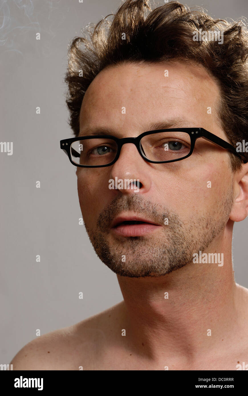 A man with glasses, no shirt and unshaven Stock Photo