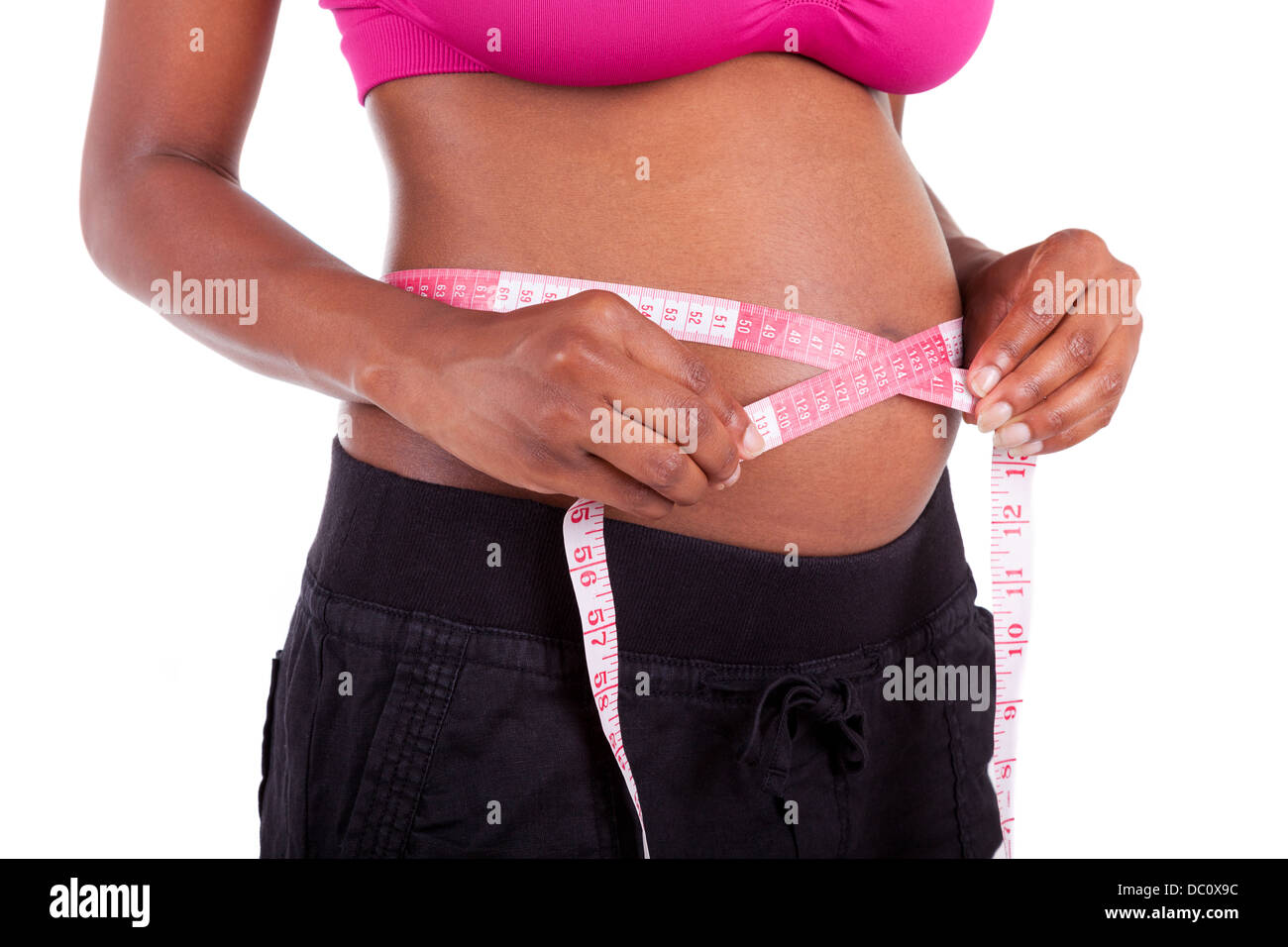 Young pregnant black woman measuring her belly, isolated on white background - African people Stock Photo