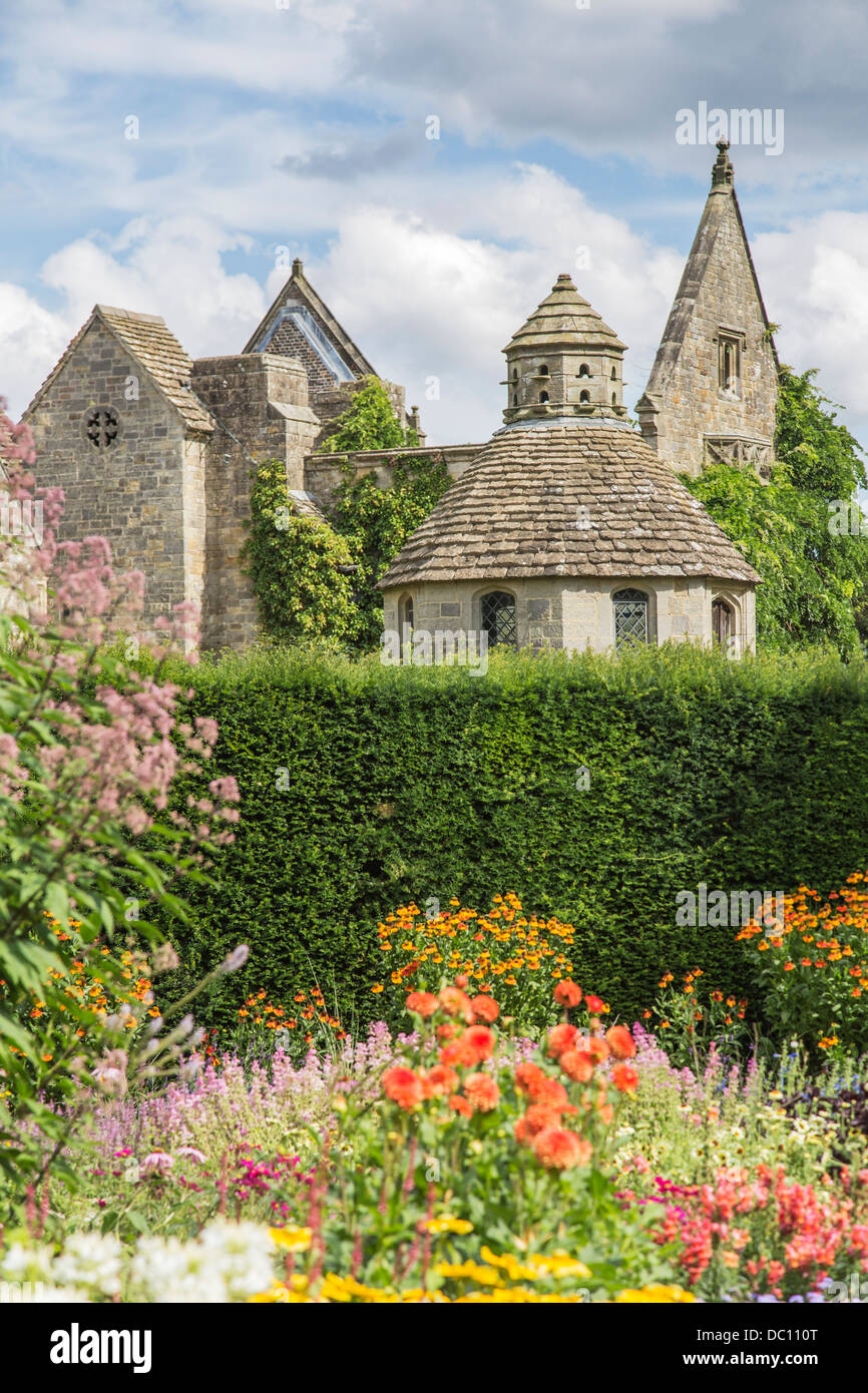 Stone dovecote and ruined facade at Nymans, Haywards Heath, West Sussex, England with colourful border of summer flowers Stock Photo