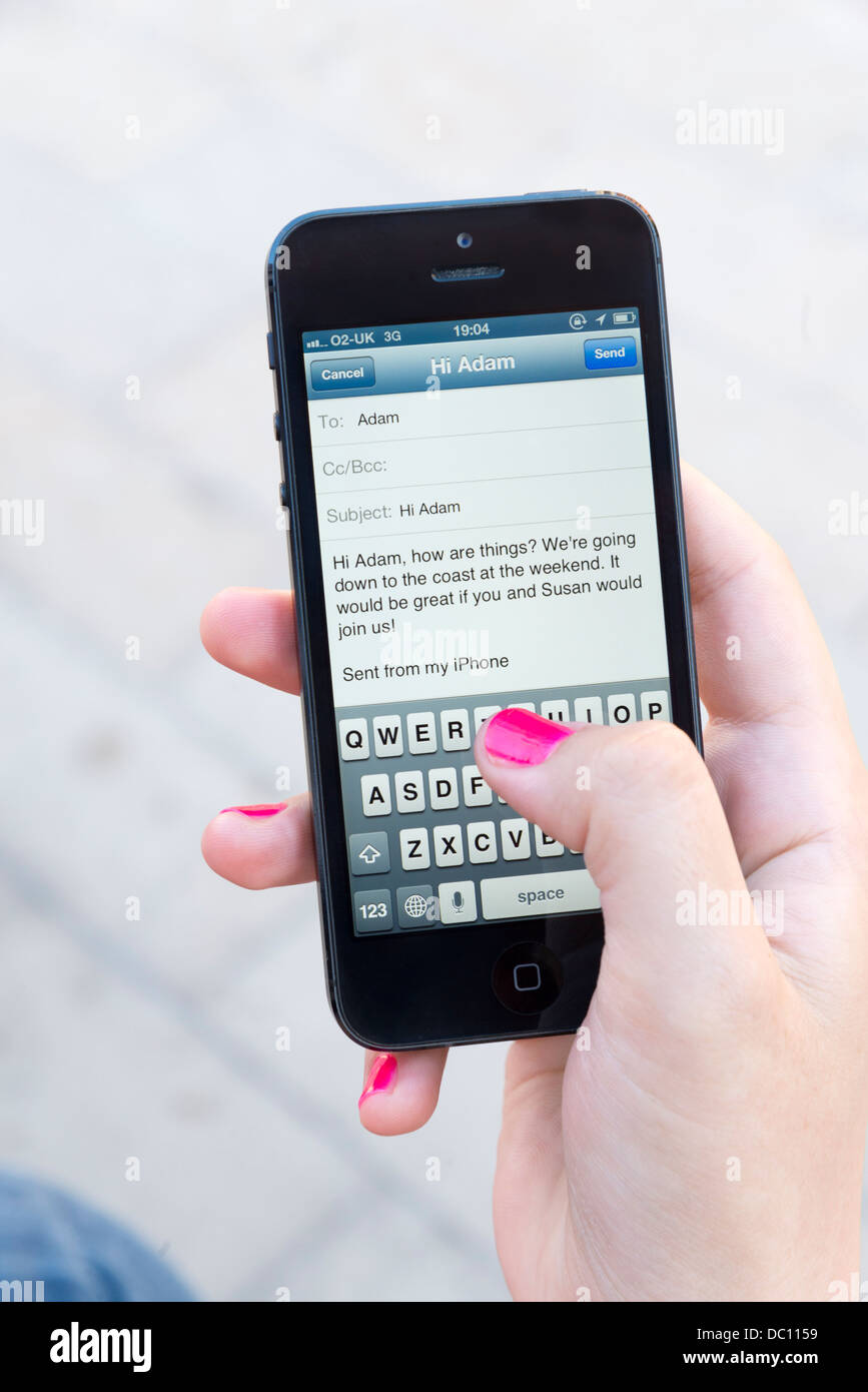 Woman sending an email on Apple iPhone 5 Stock Photo