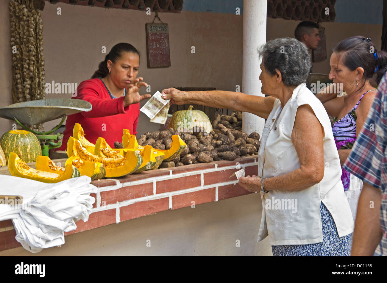 Two women paying for vegetables with Cuban pesos in small village market Stock Photo