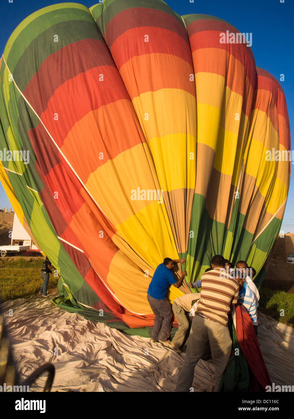 Hot air balloon being deflated and collapsed by a team of Egyptian ground crew in Luxor, Egypt. Stock Photo