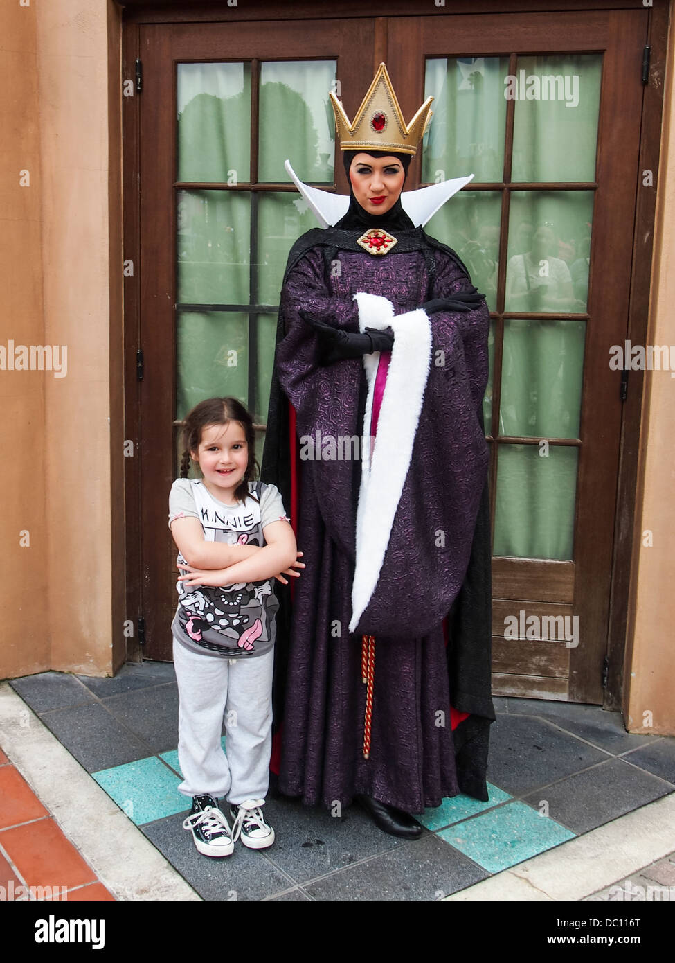 The evil queen Grimhilde, Snow Whites step mother, poses with a young girl at Disneyland Paris Stock Photo