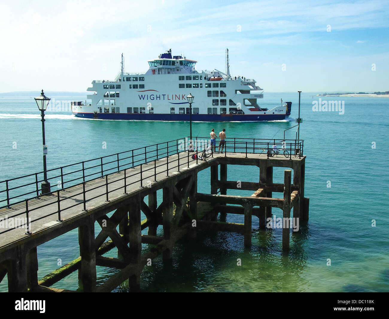 A Wightlink ferry passing a wooden jetty with people fishing at the entrance to Portsmouth harbour in the Solent, Hampshire Stock Photo