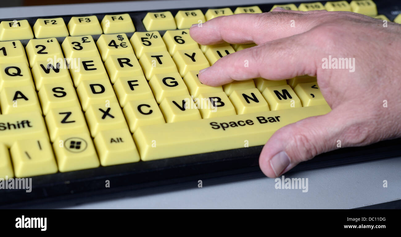 Hand of mature adult male on over size keyboard designed for use by