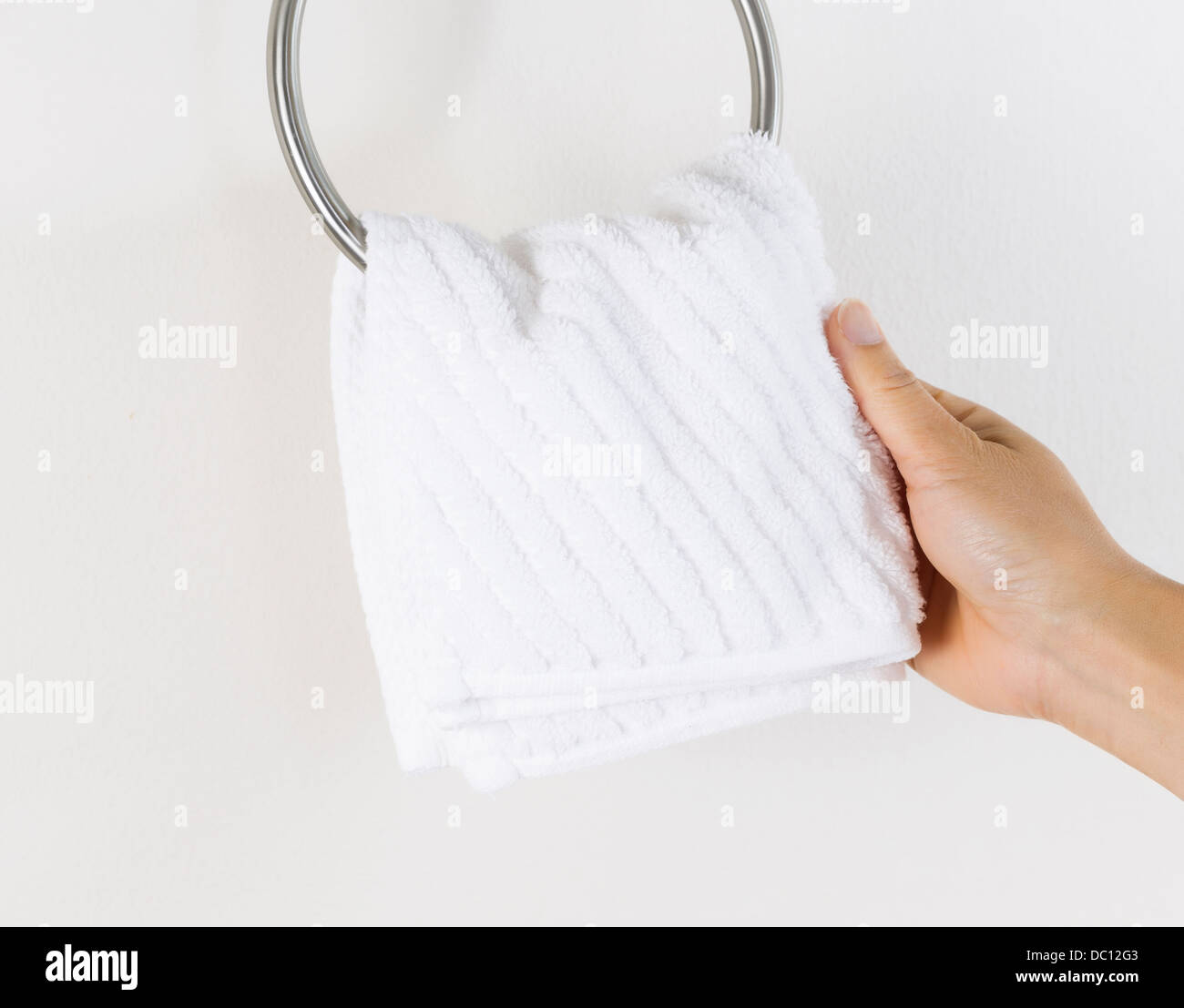 Horizontal photo of female hand putting clean white towel on wall hook Stock Photo