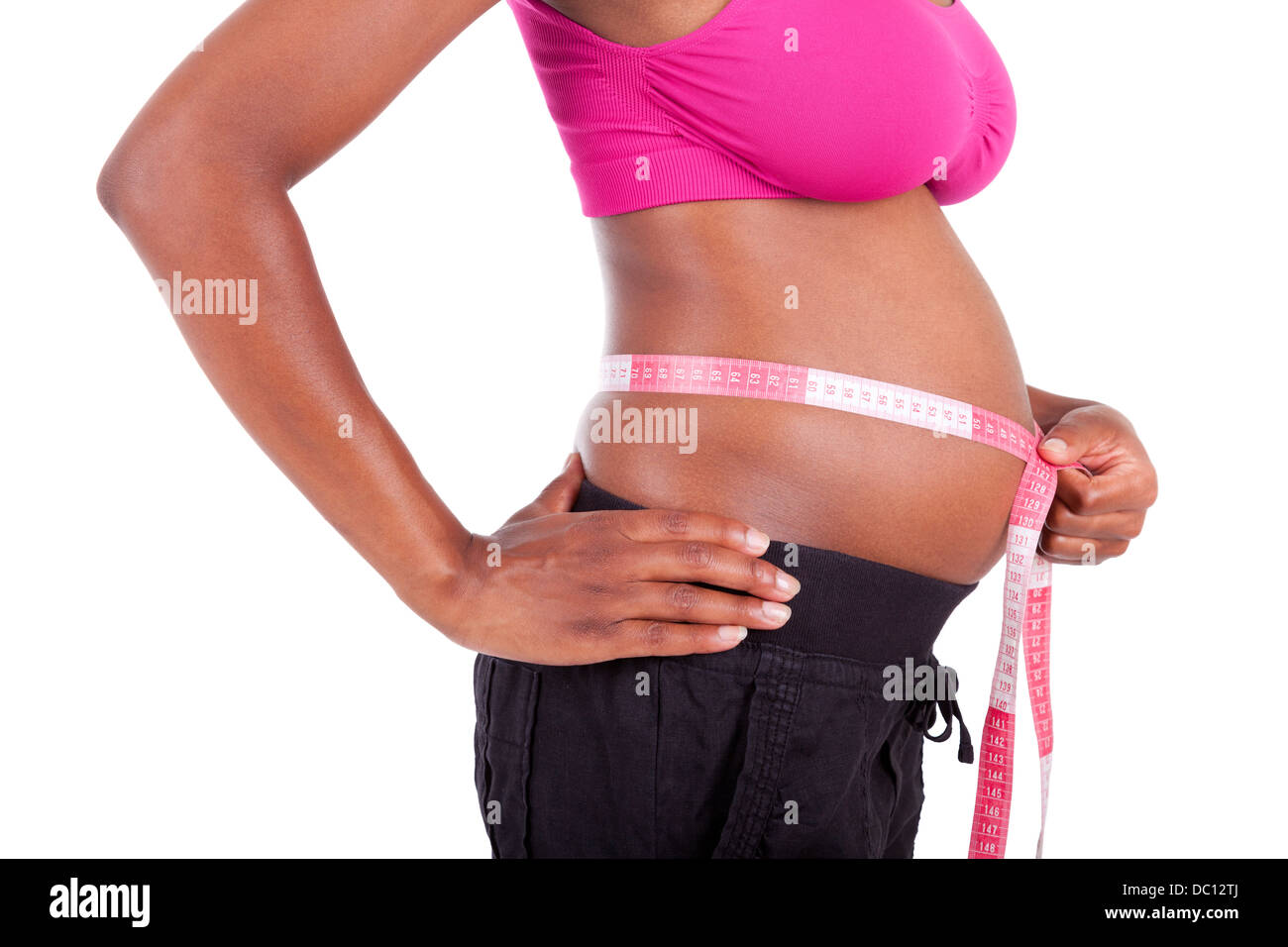 Young pregnant black woman measuring her belly, isolated on white background - African people Stock Photo