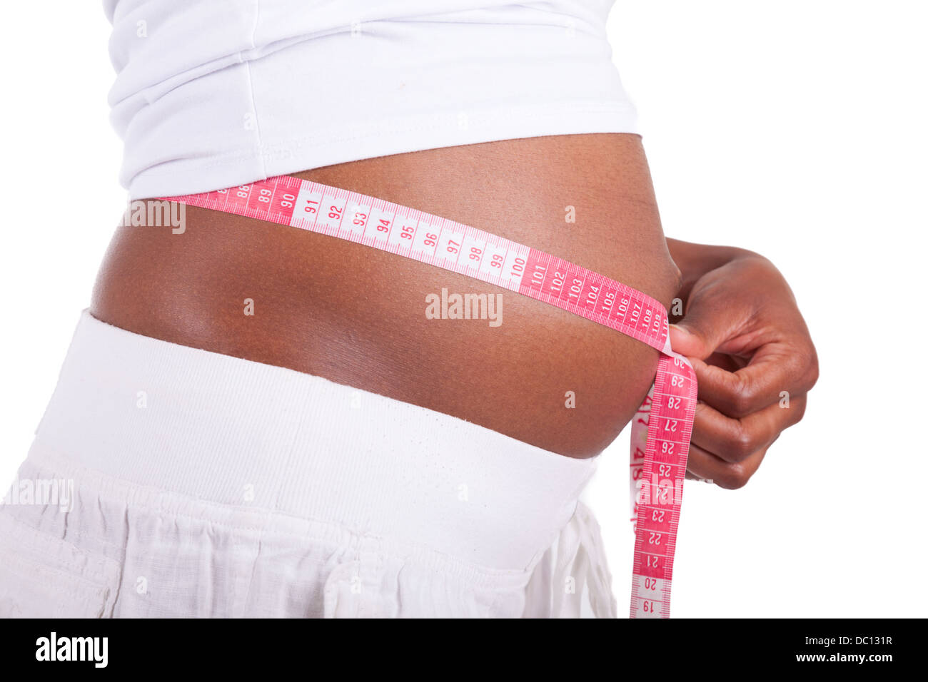 Young pregnant black woman measuring her belly, isolated on white background - African people Stock Photo