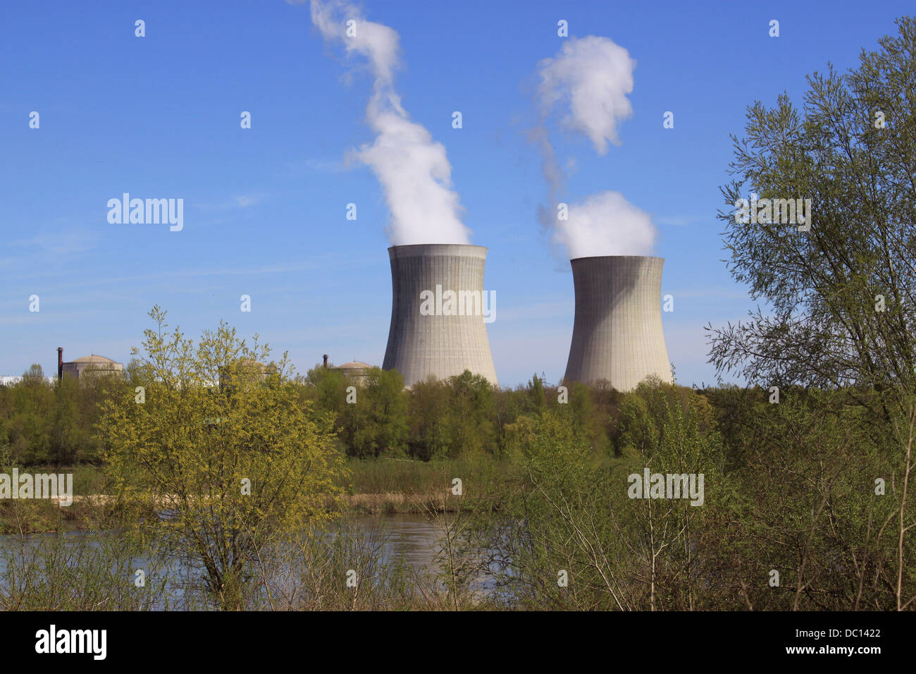 photo of an operating nuclear power plant on the banks of a river surrounded by trees Stock Photo