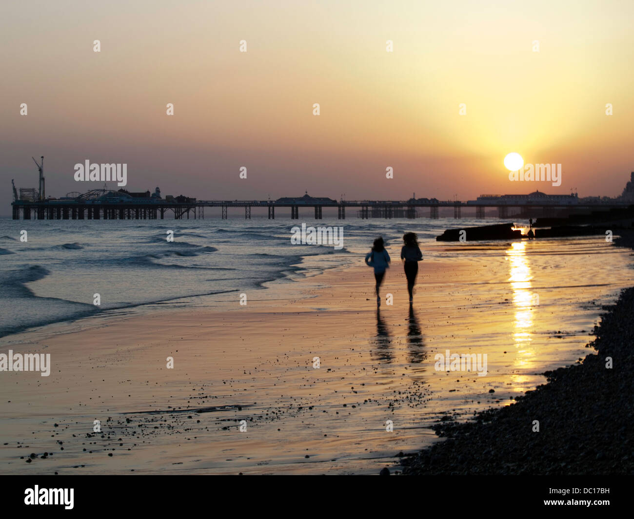 Joggers at Sunset along Brighton beach, the sun is just setting behind  Brighton Pier on this lovely Spring evening Stock Photo - Alamy