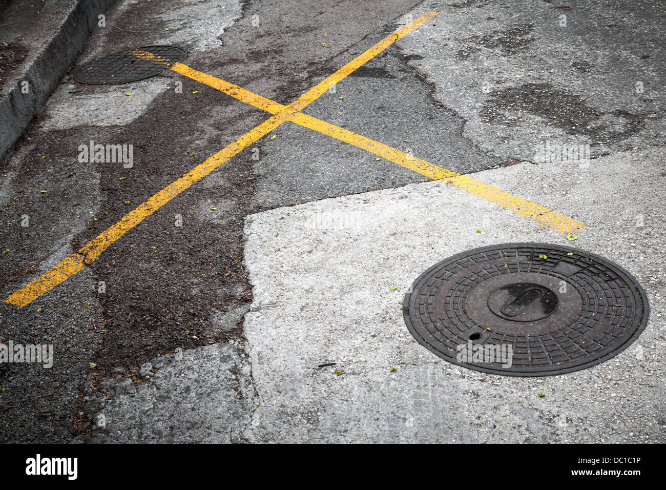 Round hatch on asphalt road with yellow marking lines Stock Photo