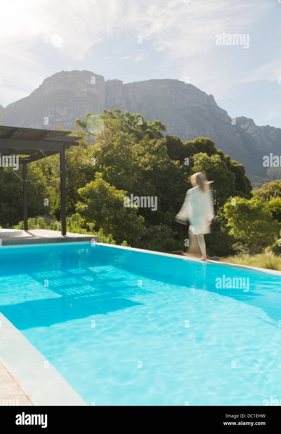 Woman walking along swimming pool Stock Photo