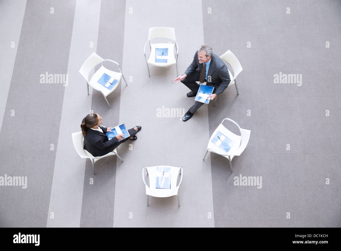 High angle view of businessman and businesswoman talking at chairs in circle Stock Photo
