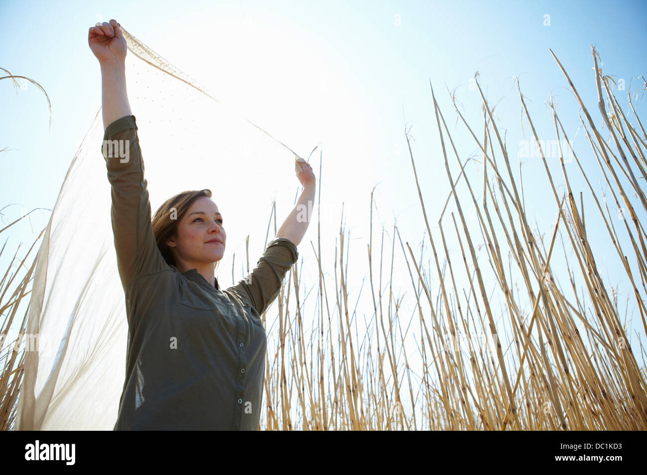 Young woman holding up scarf in reeds Stock Photo