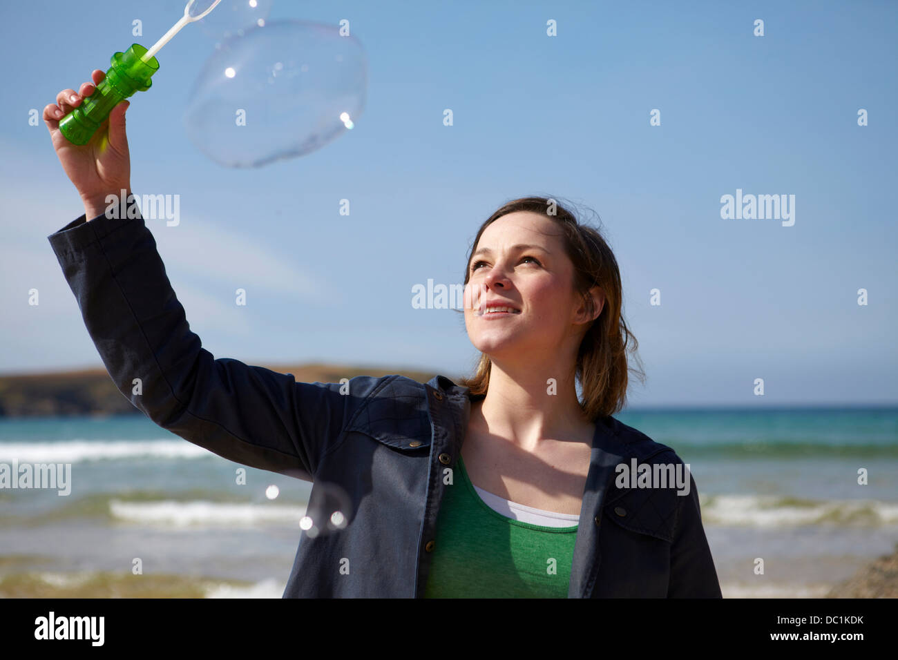 Young woman at coast with bubble wand Stock Photo