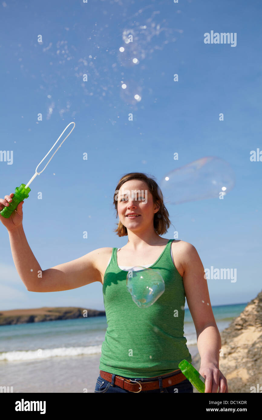 Young woman at coast playing with bubble wand Stock Photo