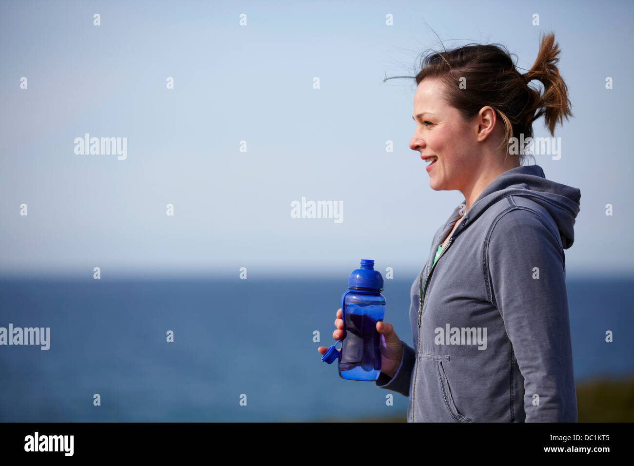 Young woman at coast taking exercise break Stock Photo