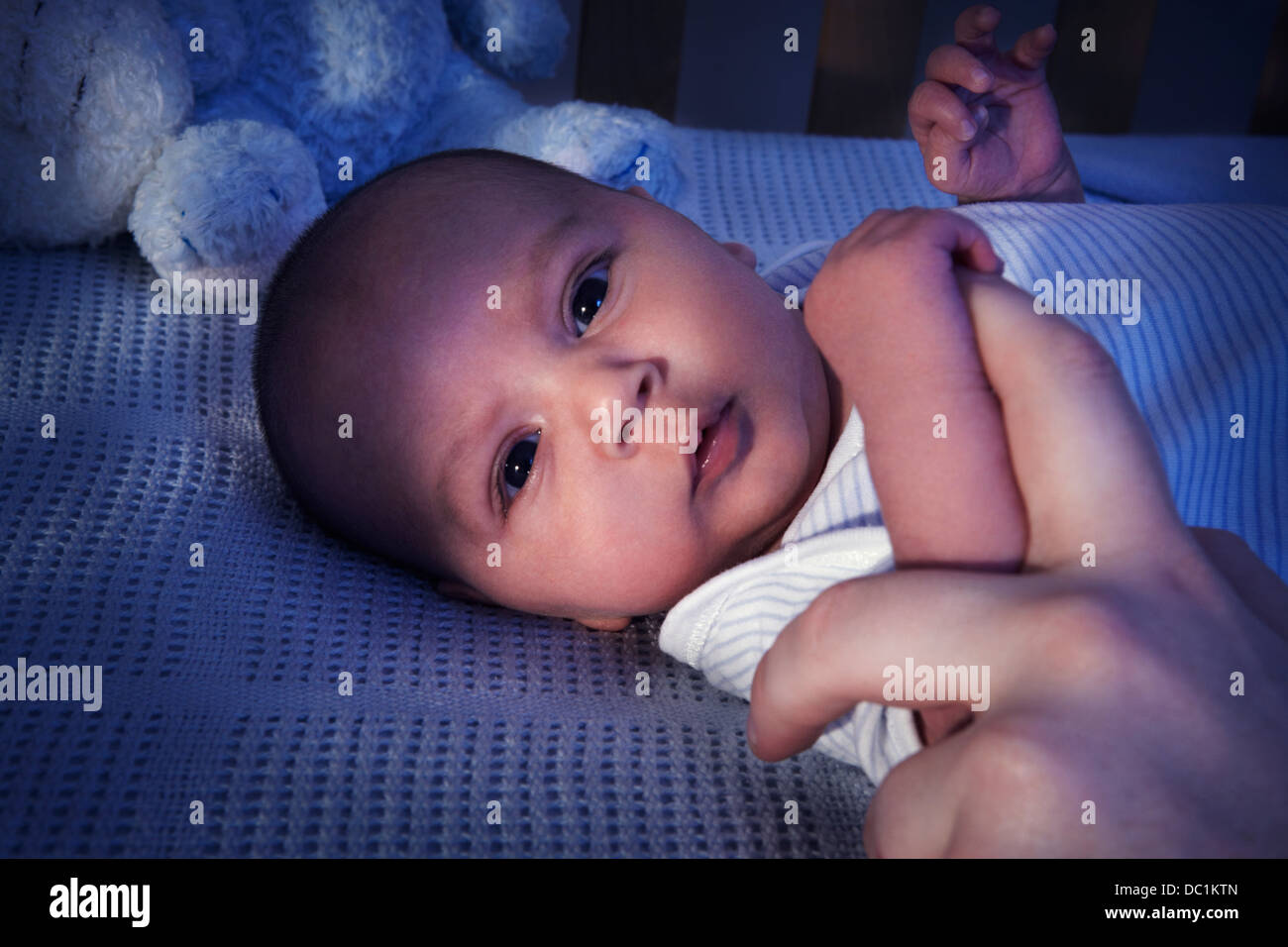 Close up of baby boy in crib at night Stock Photo