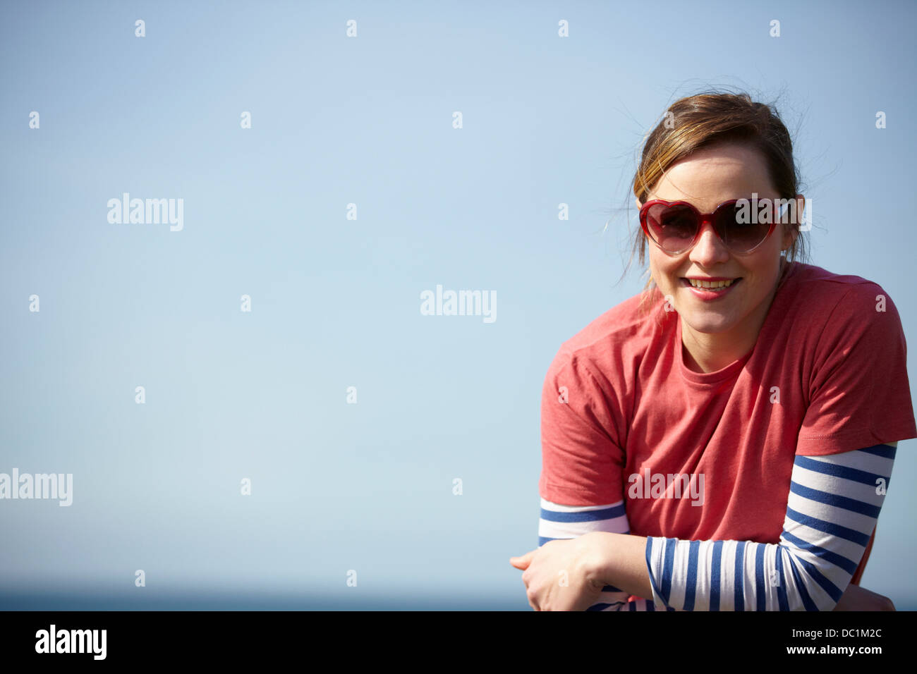 Portrait of young woman wearing heart shape sunglasses at coast Stock Photo