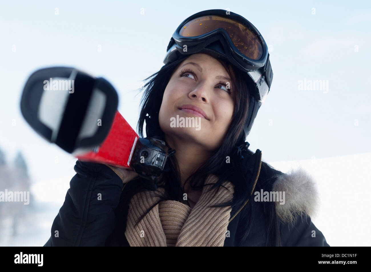 Young female wearing ski goggles and carrying skis Stock Photo