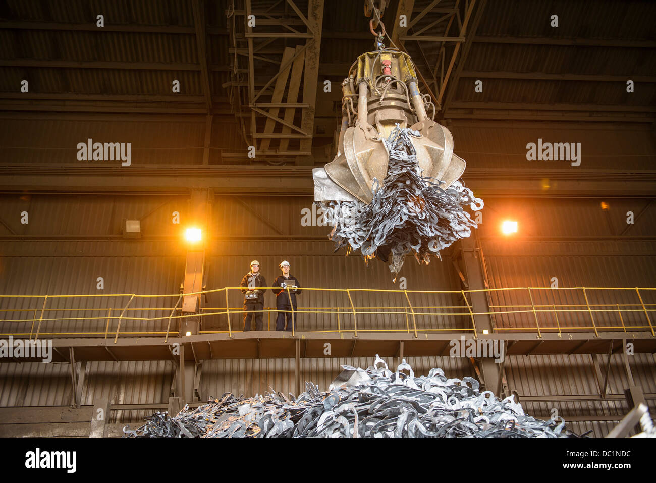 Steel workers watching mechanical grabber in steel foundry Stock Photo