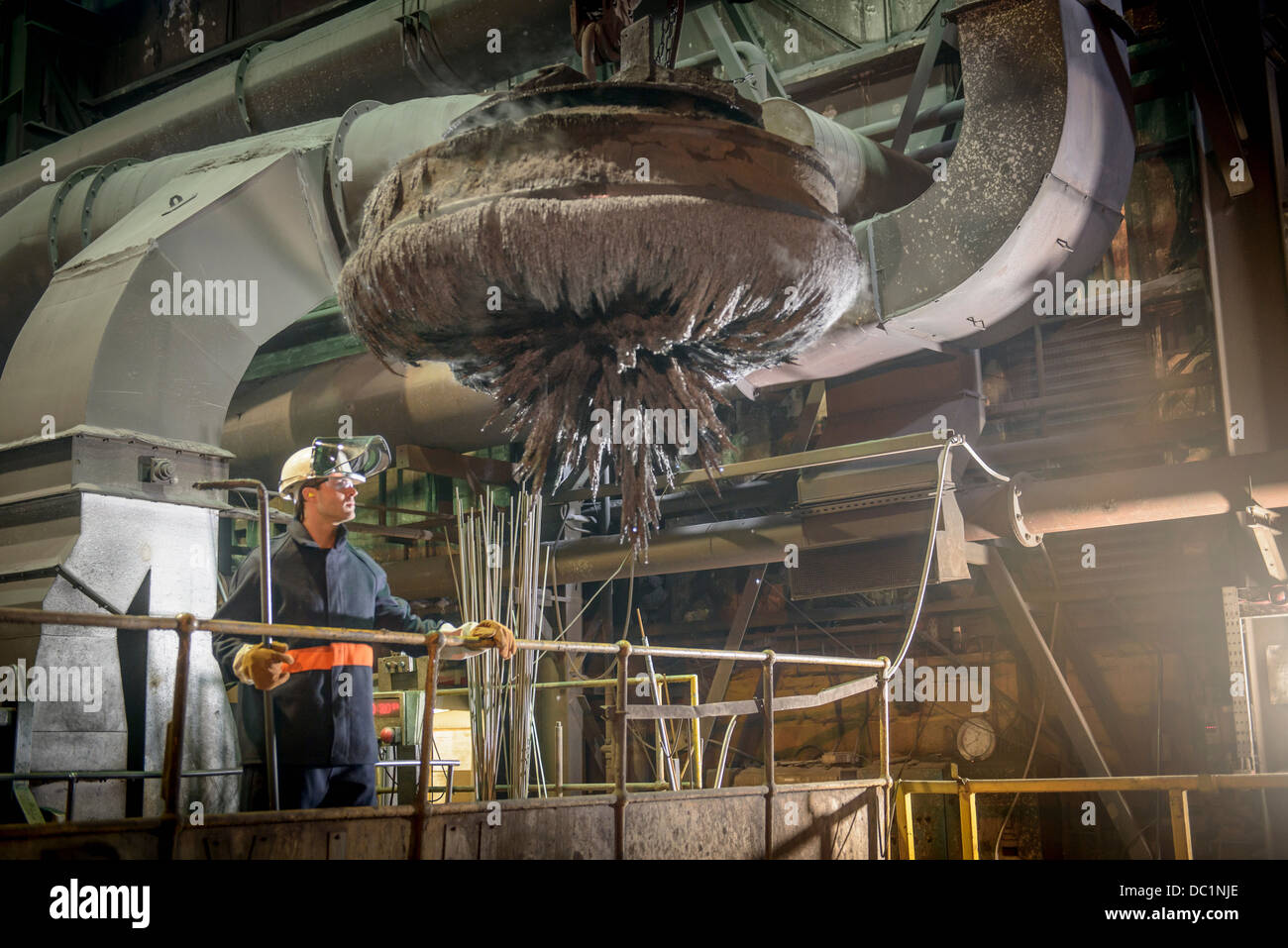 Steel worker overseeing industrial magnet at work in steel foundry Stock Photo