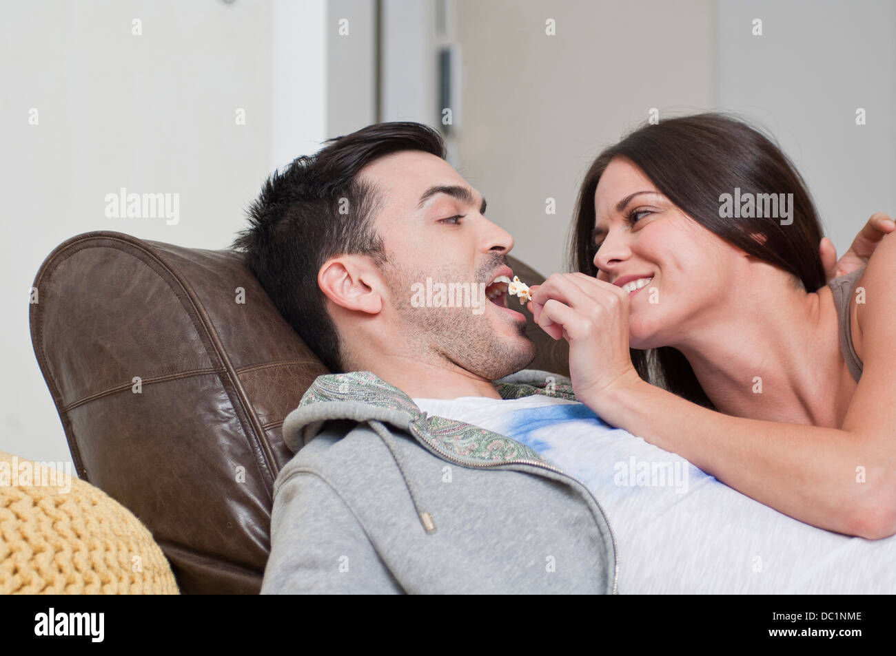Young couple lying on sofa sharing popcorn Stock Photo image image
