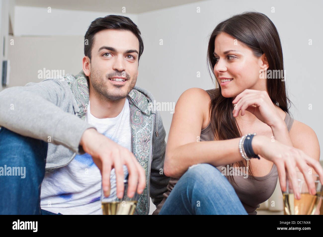 Young couple sitting down sharing glass of wine Stock Photo