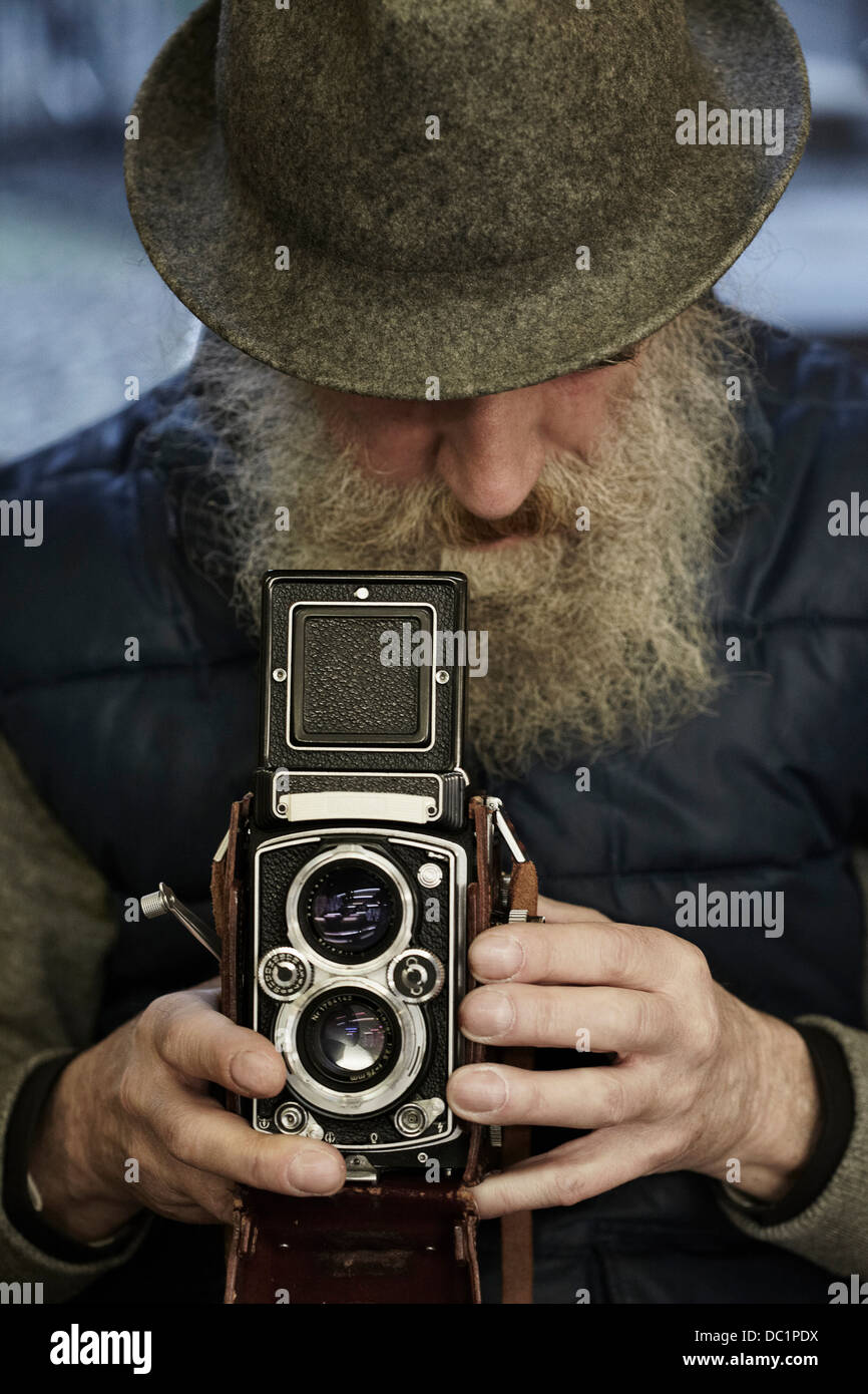 Senior man using twin lens reflex camera, close up Stock Photo