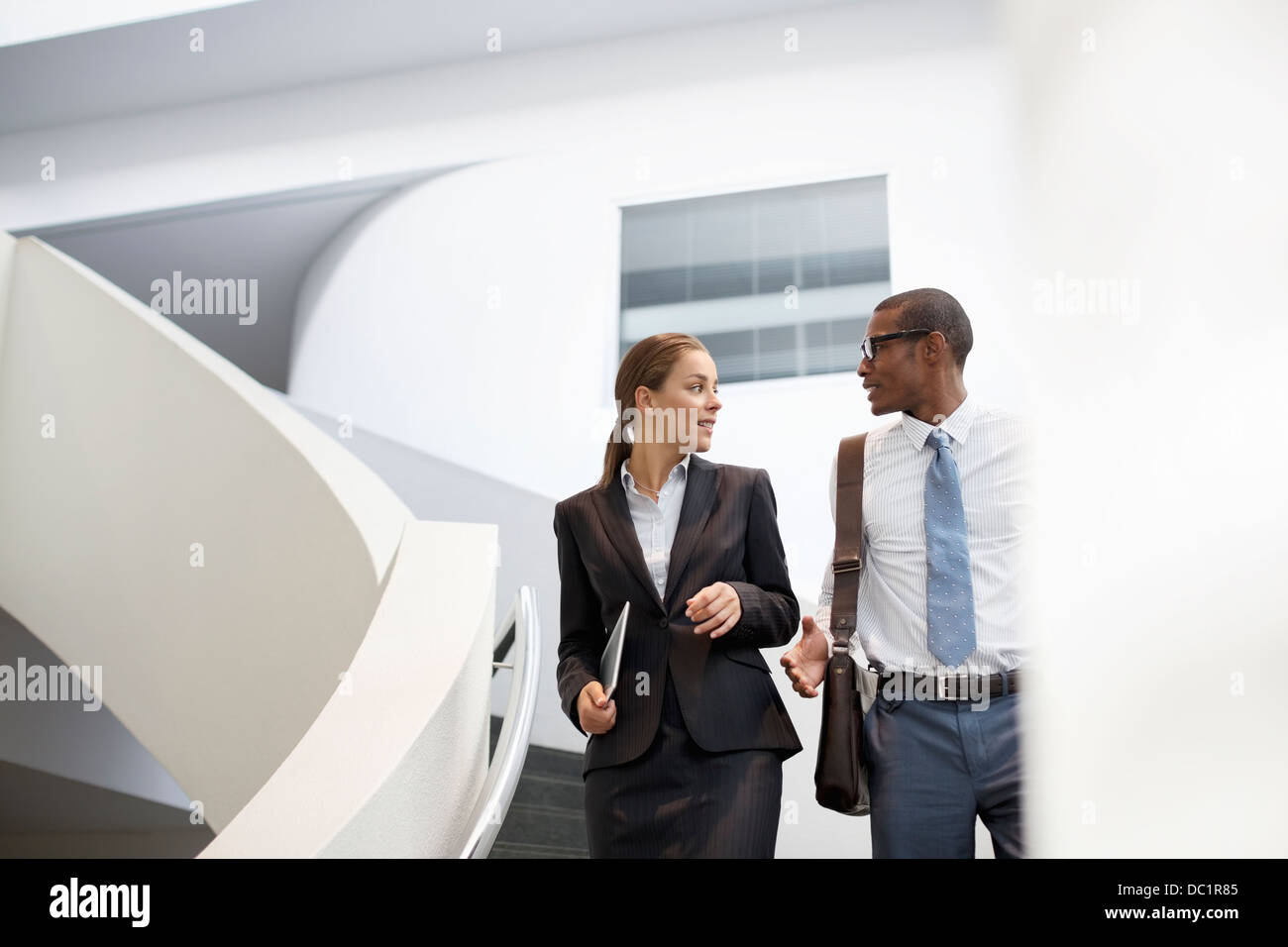 Businessman and businesswoman talking on modern staircase Stock Photo