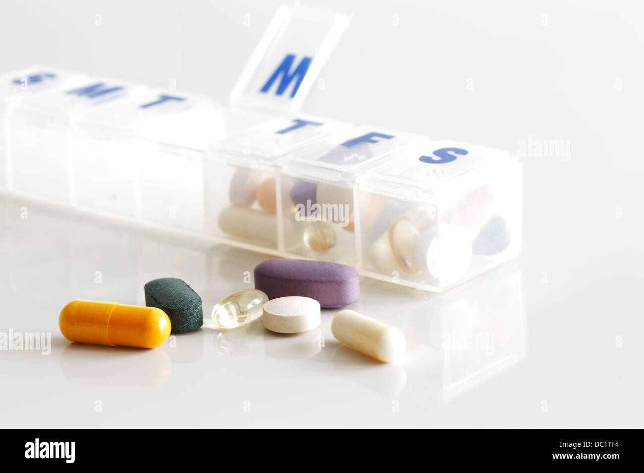 A weekly container of tablets, vitamins etc. on white reflective ceramic surface Stock Photo